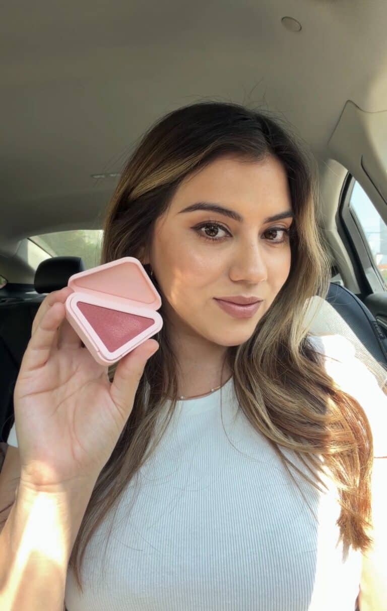 Jasmine Del Toro holding the Prada Touch cream-to-powder blush in shade Dahlia, showing the pink triangle compact open