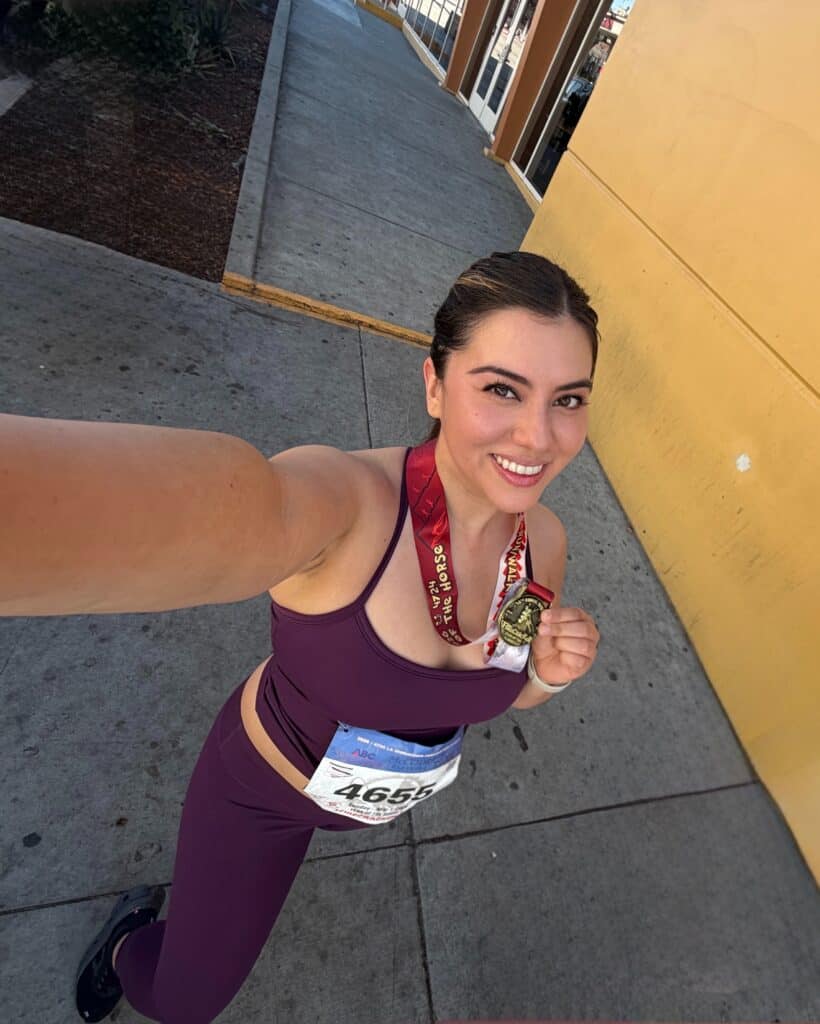 Jasmine smiling and holding a race finisher medal after completing a run